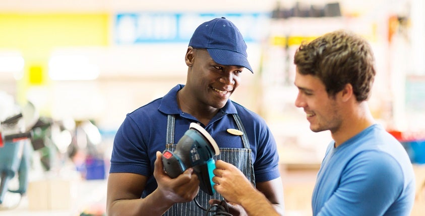friendly hardware store worker showing customer a sander